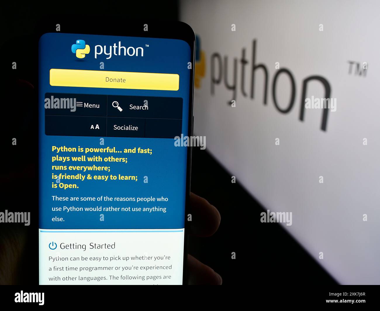 Person, die ein Mobiltelefon hält, mit der Webseite der Organisation Python Software Foundation (PSF) vor dem Logo. Konzentrieren Sie sich auf die Mitte des Telefondisplays. Stockfoto