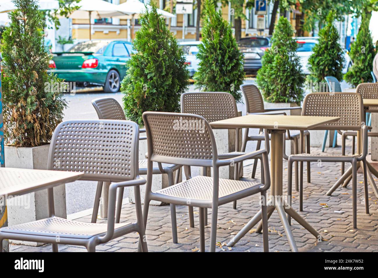 Straßencafé mit Korbmöbeln und grünen Thujas entlang der Straße Stockfoto