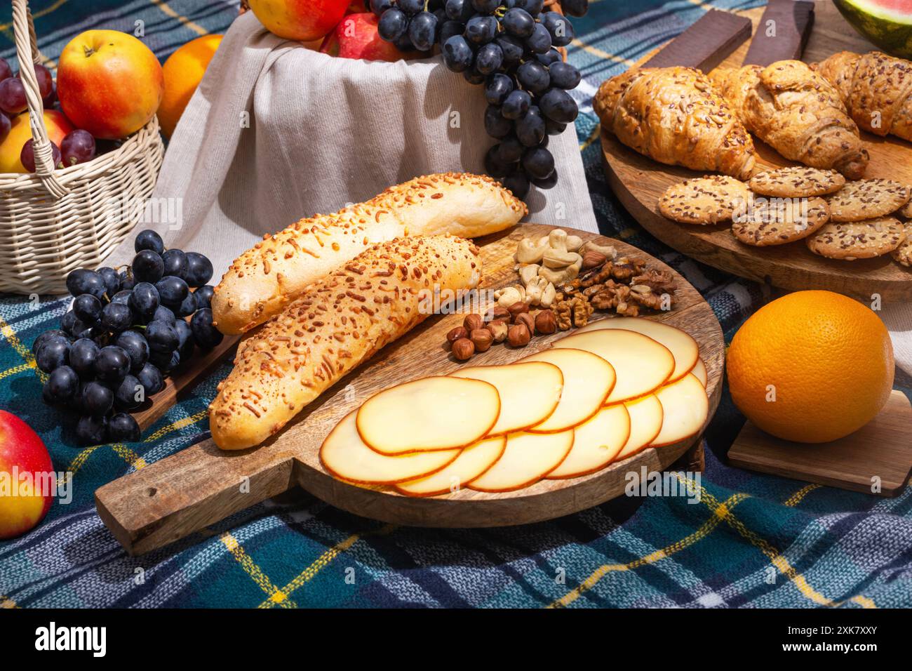 Blick auf verschiedene Speisen für das Sommer-Picknick auf karierter Decke, Nahaufnahme mit selektivem Fokus. Das Konzept der Sommererholung am Wochenende Stockfoto