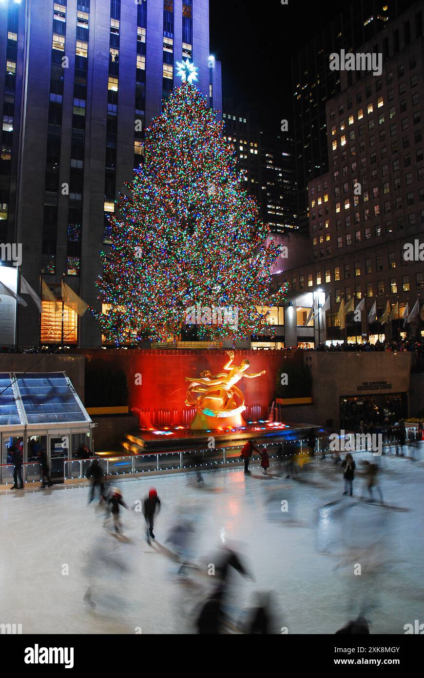 Eisläufer gleiten während der Weihnachtszeit am beleuchteten Weihnachtsbaum im Rockefeller Center, New York City, vorbei Stockfoto