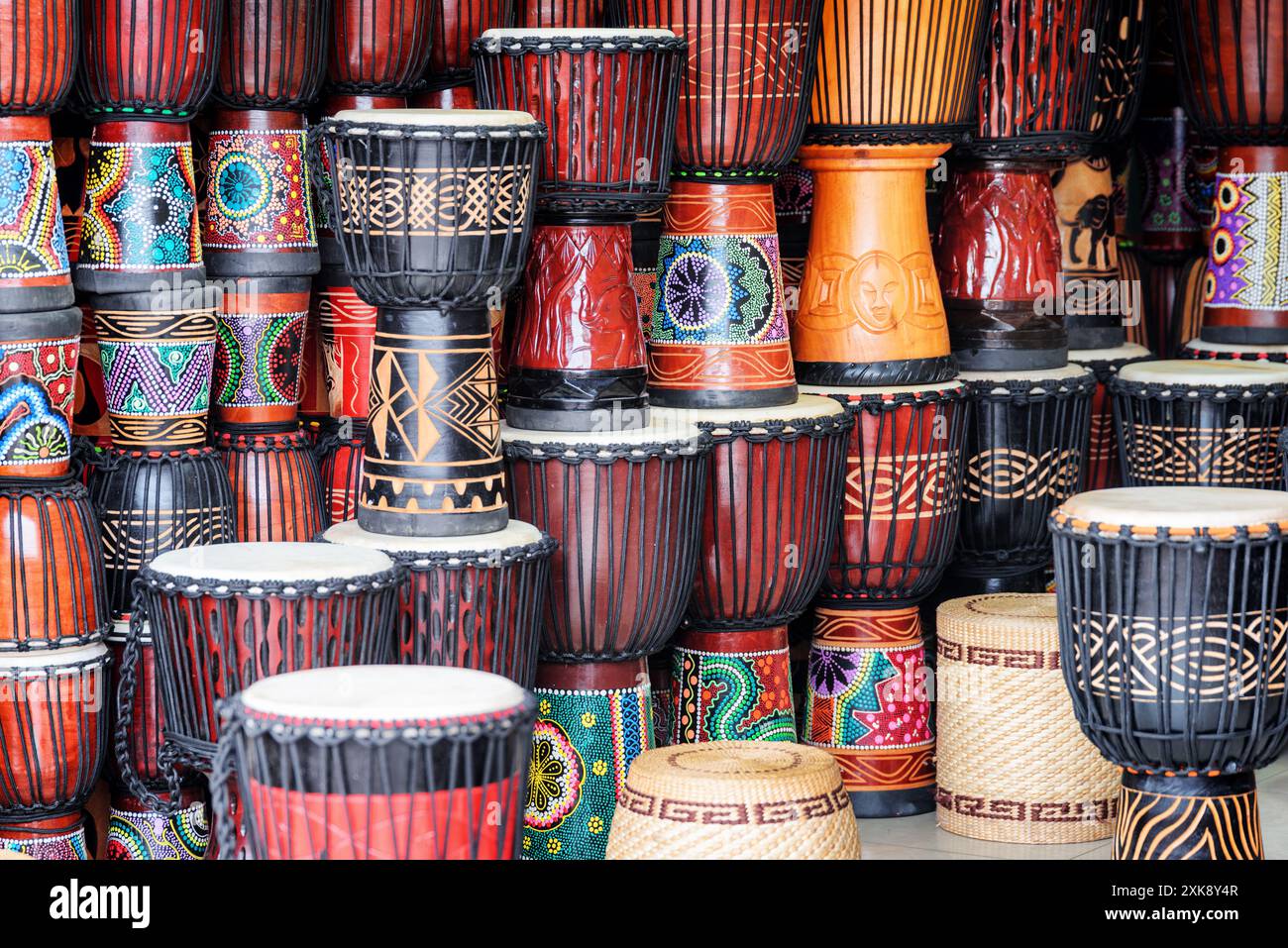 Farbenfrohe Reihen von Djembe-Trommeln aus Holz im Souvenirshop Stockfoto