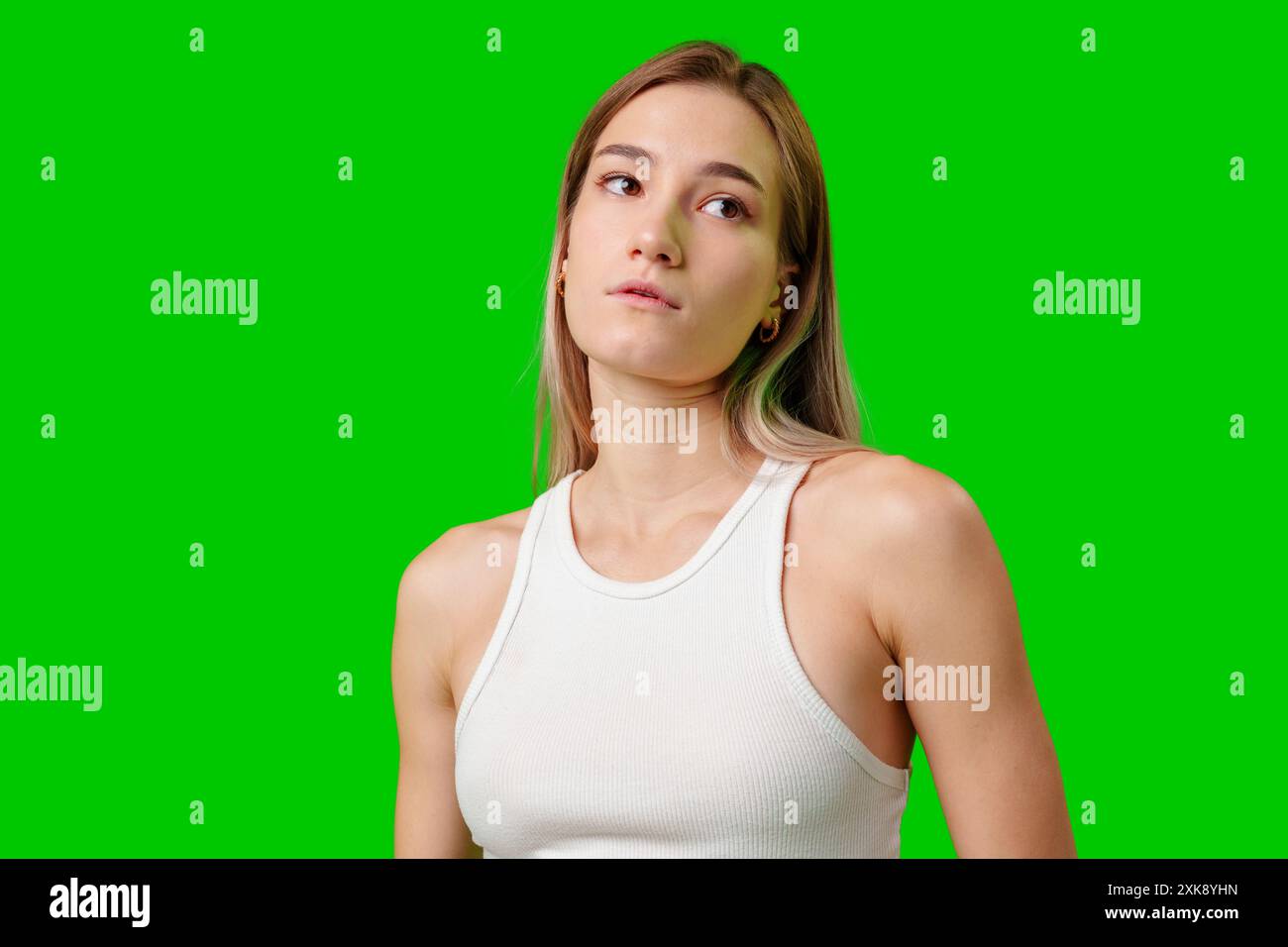 Junge Frau im weißen Tank Top gegen Green Screen Stockfoto