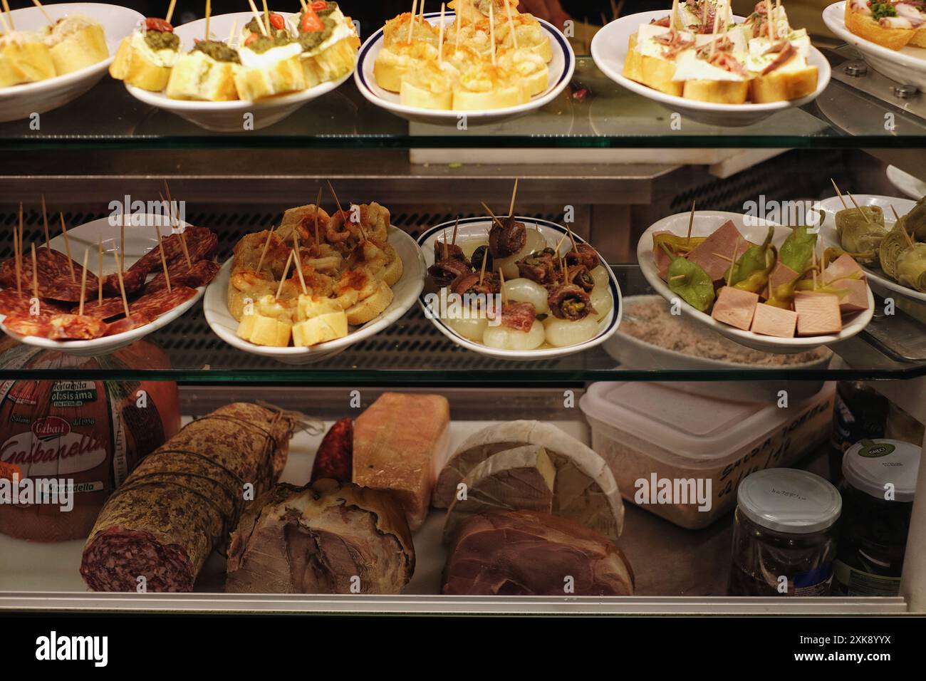 Cicchetti-Teller in einer Glasvitrine mit Schinken und Salami auf dem unteren Regal in einer kleinen Bar in Dorsoduro, Venedig, Italien Stockfoto