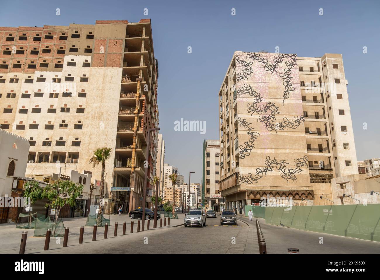 Das wunderschöne Kalligraphie-Wandgemälde an der Mauer der Stadt Dschidda in Saudi-Arabien, mit leichtem Verkehr auf der Straße. Stockfoto