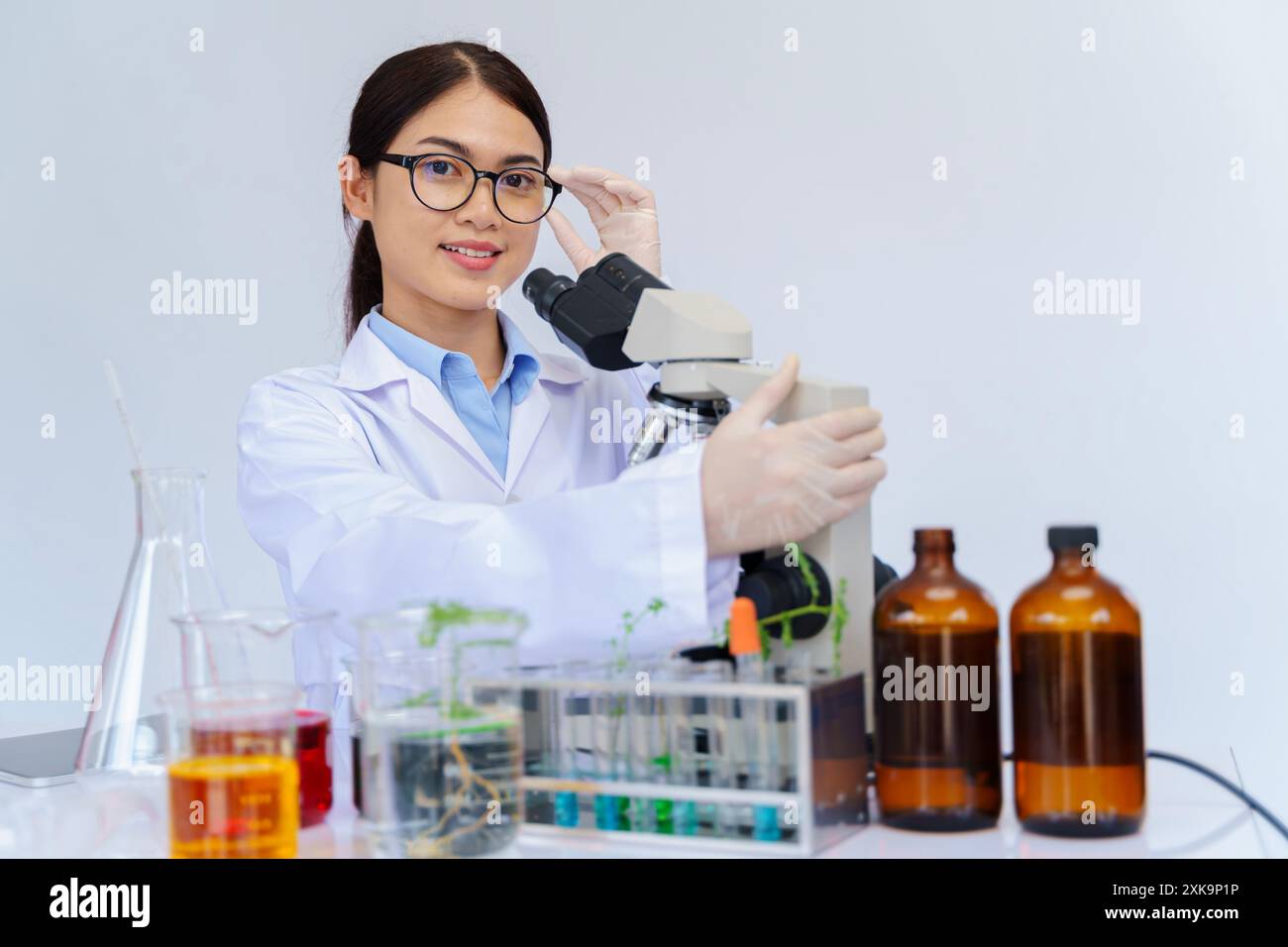 Wissenschaftlerin, die durch ein Mikroskop in einem Labor schaut. Wissenschaftler Laborassistent mit medizinischem Kleid, die einige Forschung, Medizin Wissenschaft Konzept. Stockfoto