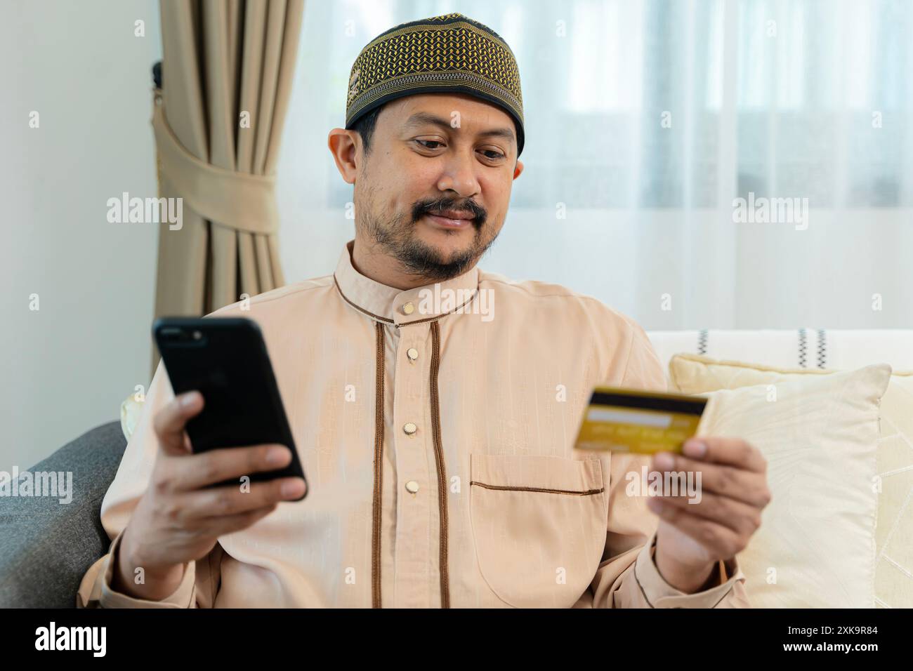 Fröhlicher arabischer Mann mit Kreditkarte und Smartphone-Shopping online. Online-Shopping mit Smartphone. E-Commerce, Internet-Banking-Konzept. Stockfoto