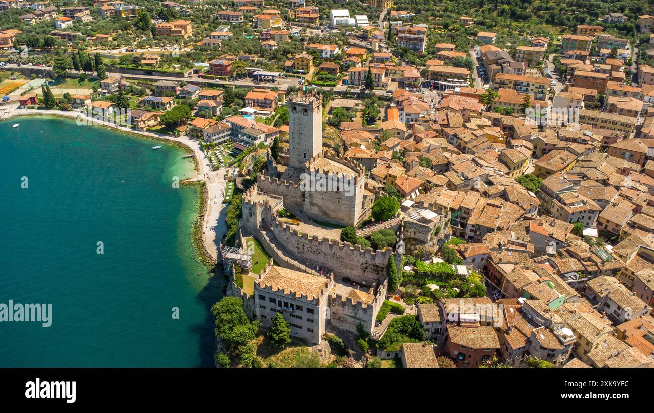 Malcesine, Gardasee, Italien - 20. Juli 2024: Luftaufnahme der malerischen Stadt Malcesine am Gardasee in Italien, das historische Schloss und die charmante Altstadt, die sich entlang des klaren blauen Wassers erstreckt *** Luftaufnahme der malerischen Stadt Malcesine am Gardasee in Italien, die historische Burg und die charmante Altstadt, die sich entlang des klaren, blauen Wassers erstrecken Stockfoto