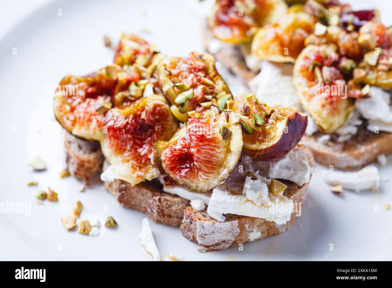 Frühstück Toast mit Fetakäse, Feigen und Pistazien auf weißem Teller, weißem Hintergrund. Stockfoto