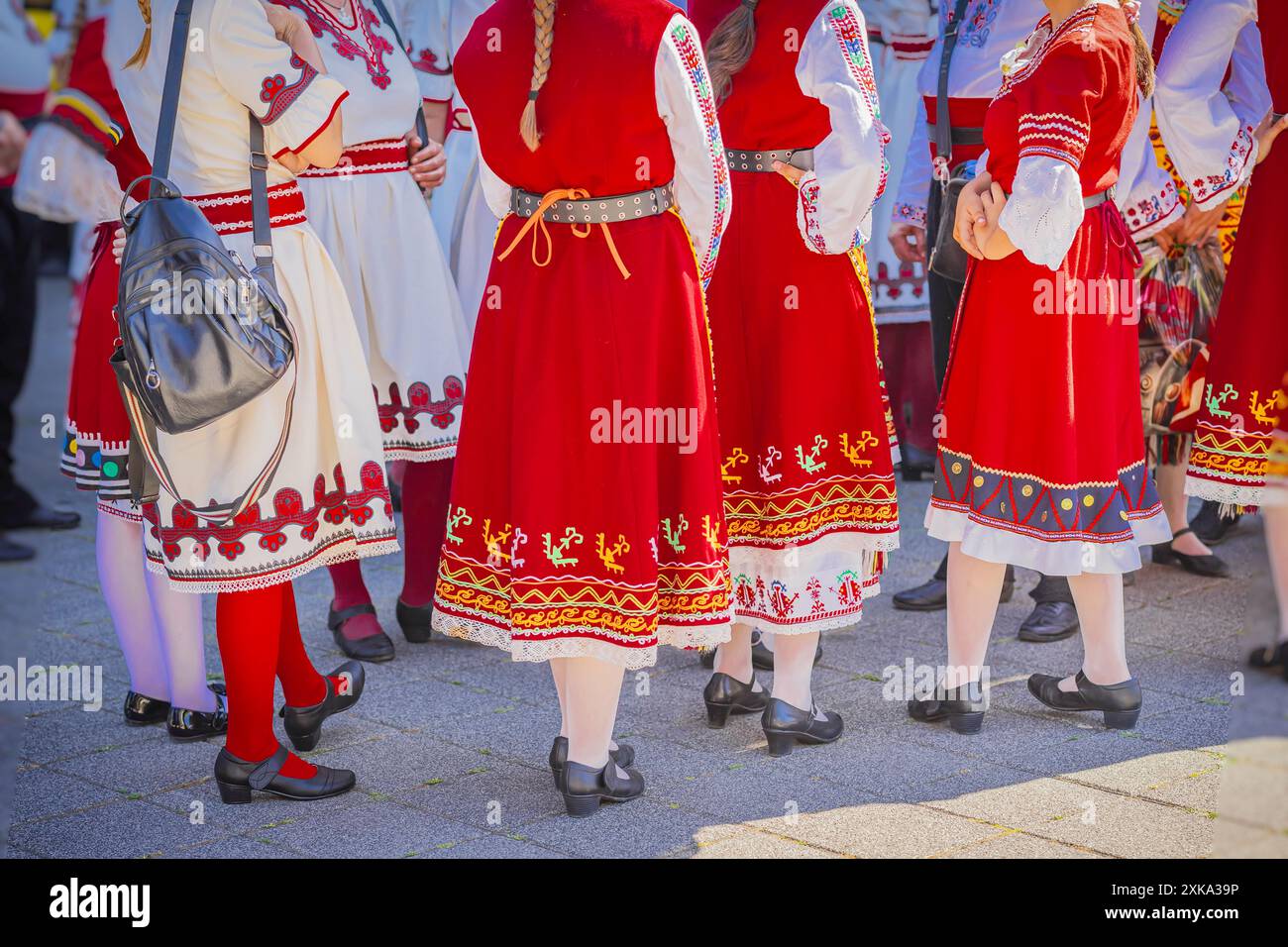 Eine Gruppe von unbekannten Frauen, die in hellen traditionellen bulgarischen Volkstrachten mit bunten Mustern und Stickereien gekleidet sind Stockfoto