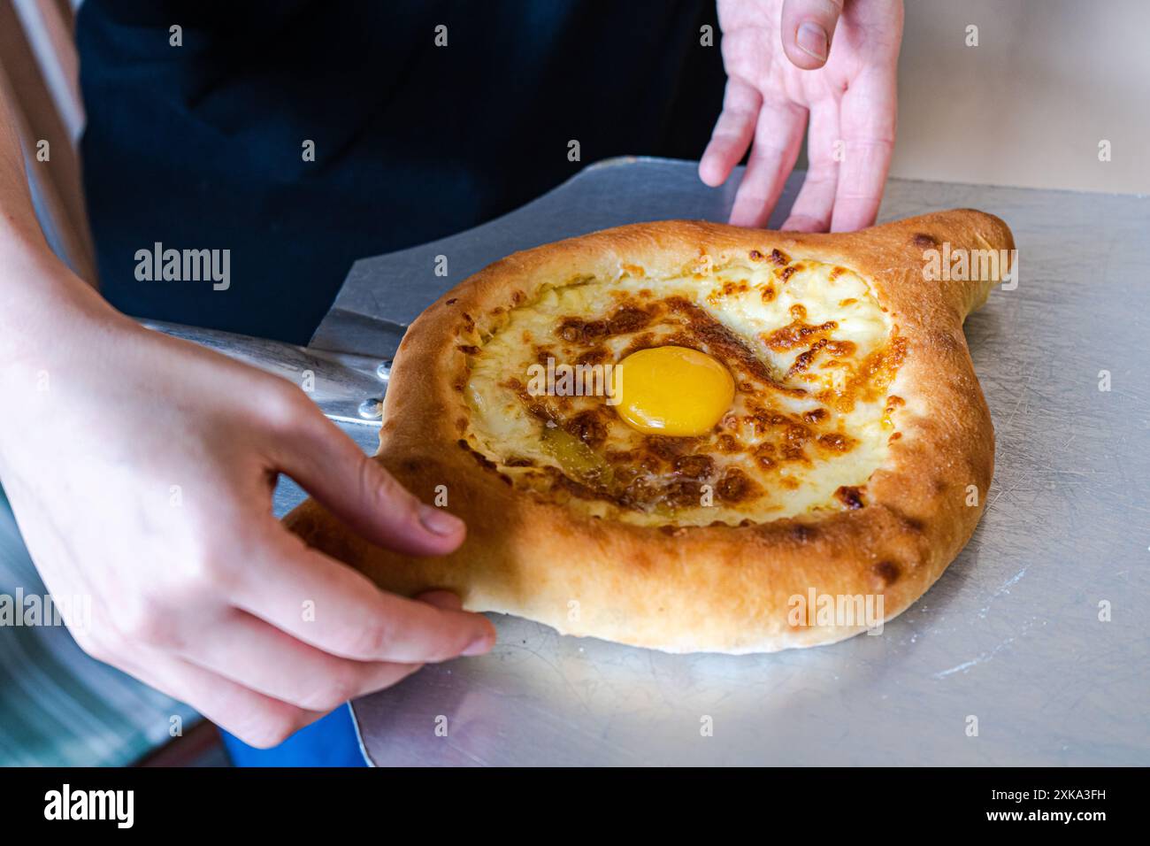 Adjarian Khachapuri in den Händen des Küchenchefs Stockfoto