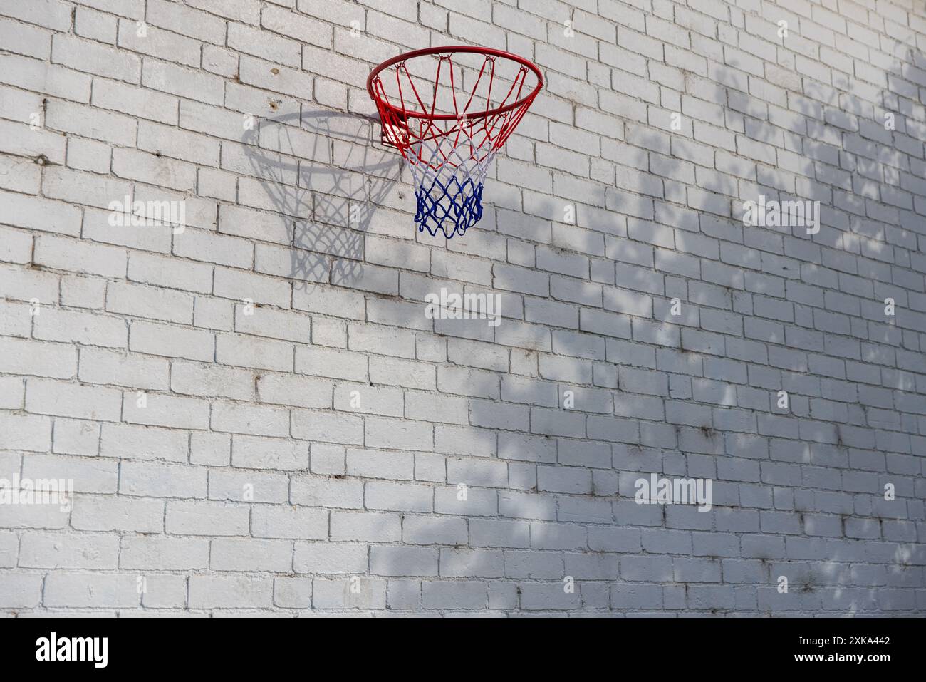 Urban Basketballkorb vor weißer Ziegelwand mit Schatten Stockfoto