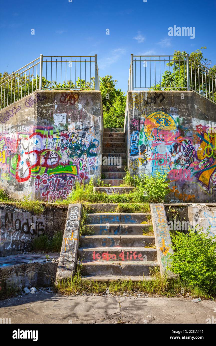 Mit Graffiti bedeckte alte Betongebäude, die von Unkraut überholt wurden Stockfoto