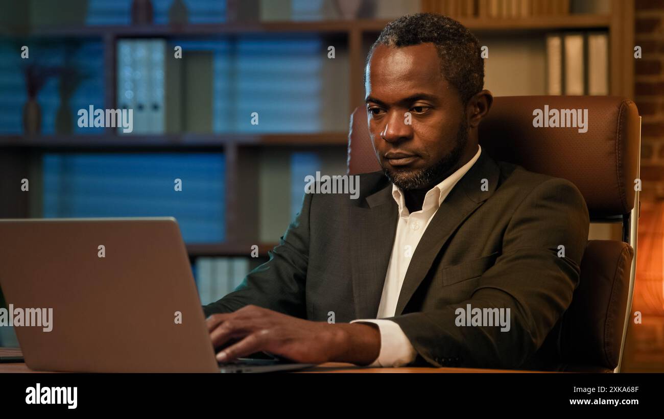 Erwachsener afroamerikanischer Geschäftsmann, der auf Laptop im Büro arbeitet ungesunder müder Mann, der unter Kopfschmerzen leidet, fühlt Schmerz Druck Müdigkeit durch Überarbeit Stockfoto