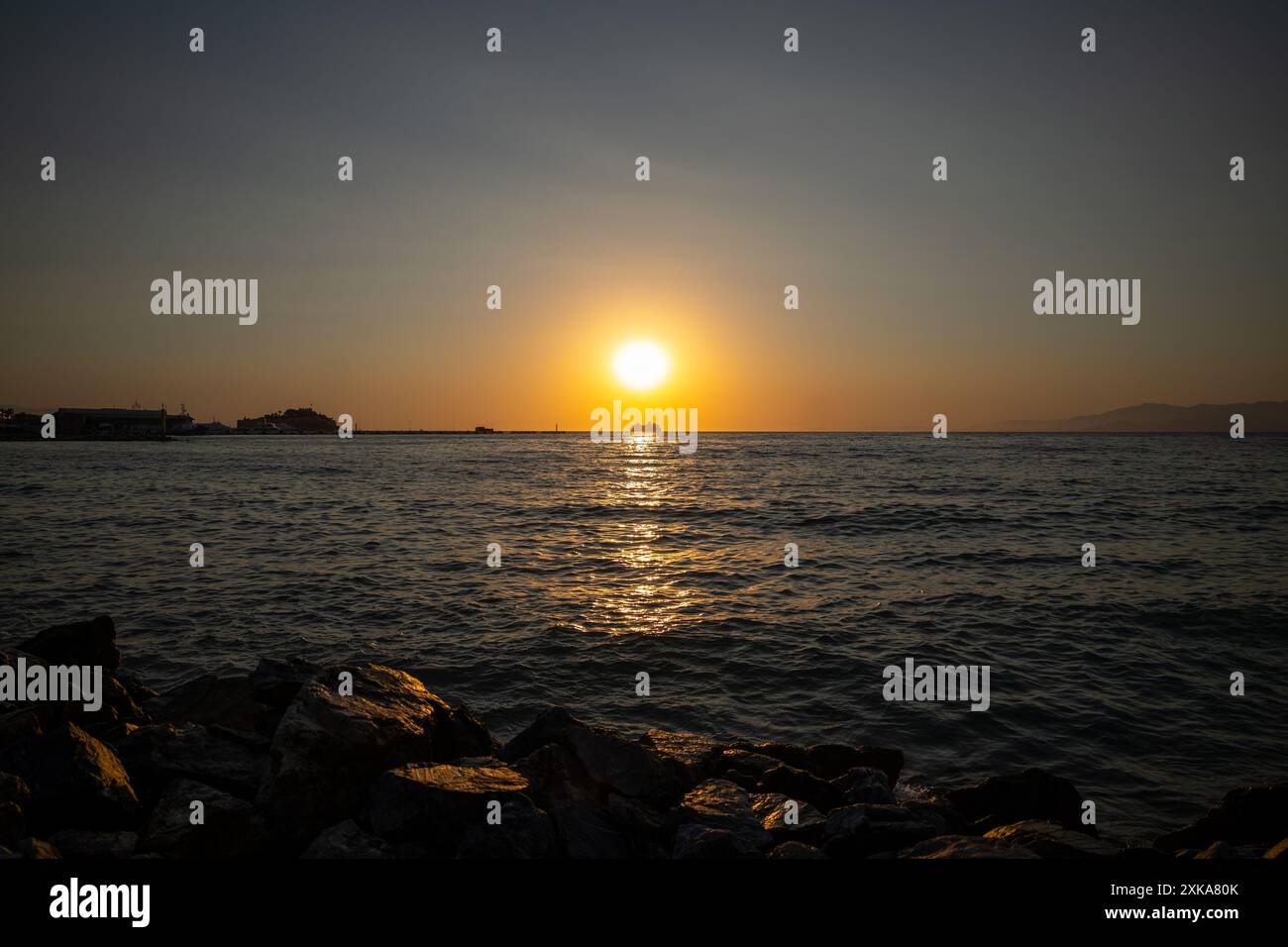 Blick auf den Sonnenuntergang am Strand mit der Silhouette eines großen Passagierschiffs Stockfoto