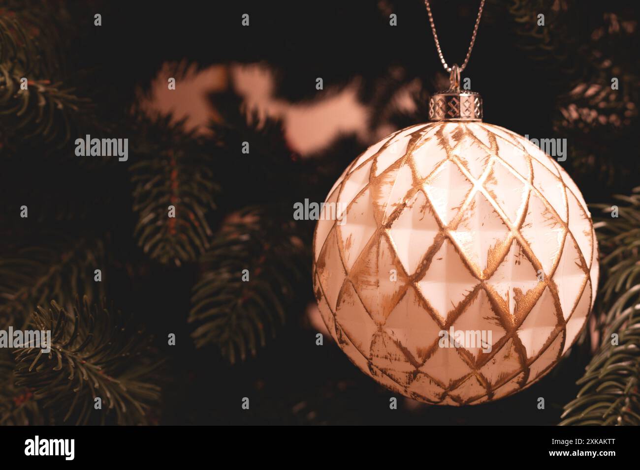 Weiße Weihnachtskugel mit goldenem Glitzer hängt an einer Tanne. Platz für Text. Stockfoto