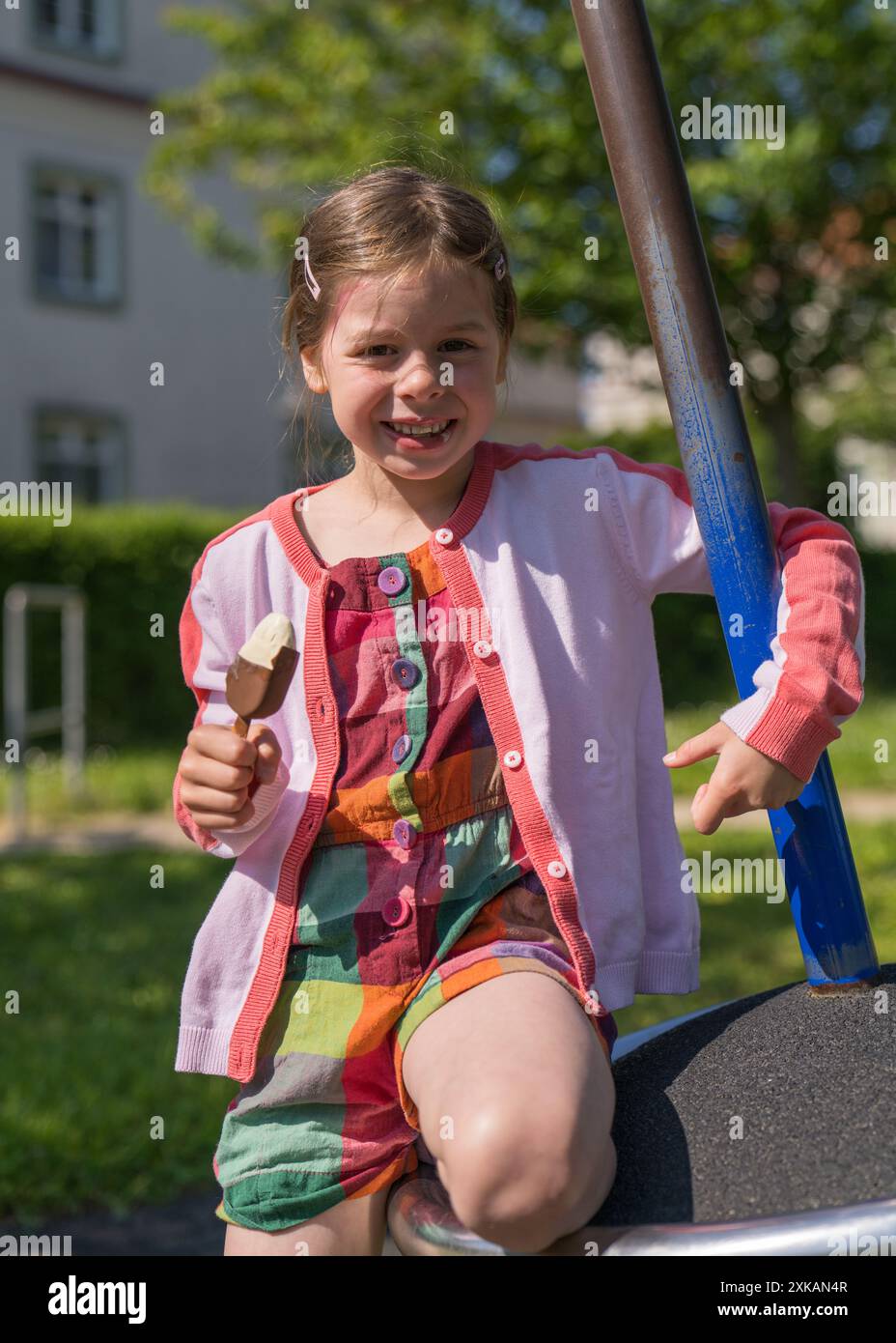 Ein kleines Mädchen hält Eis in der Hand und schaut in die Kamera. Glückliches, fröhliches Kind auf einem Spaziergang und Eis. Stockfoto