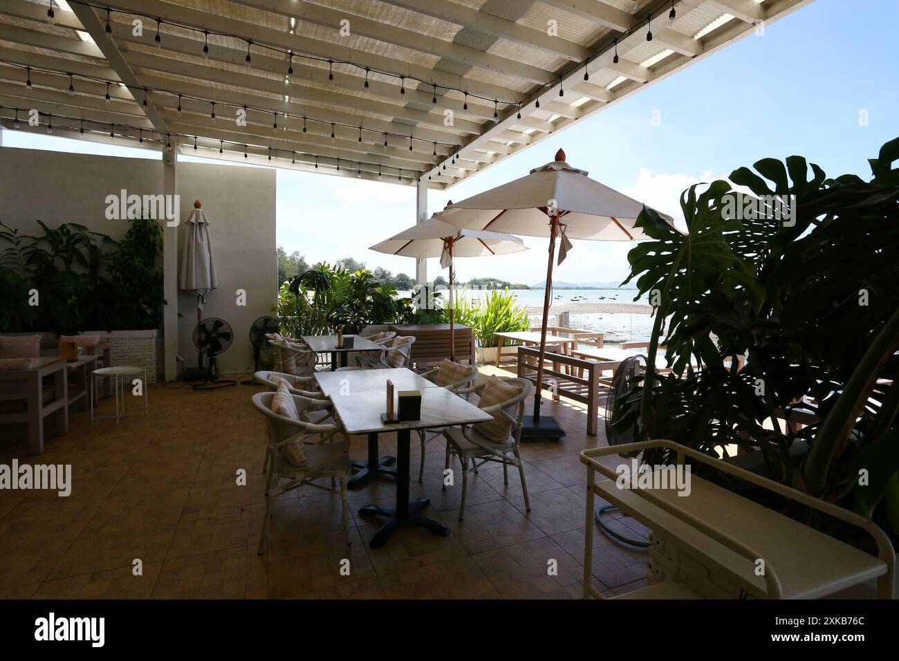 Ein Tisch zum Essen in einem Restaurant an der trockenen Küste mit Blick auf Sand, Felsen und Himmel an einem klaren Tag in Samae San Bay, Provinz Chonburi, Thaila Stockfoto