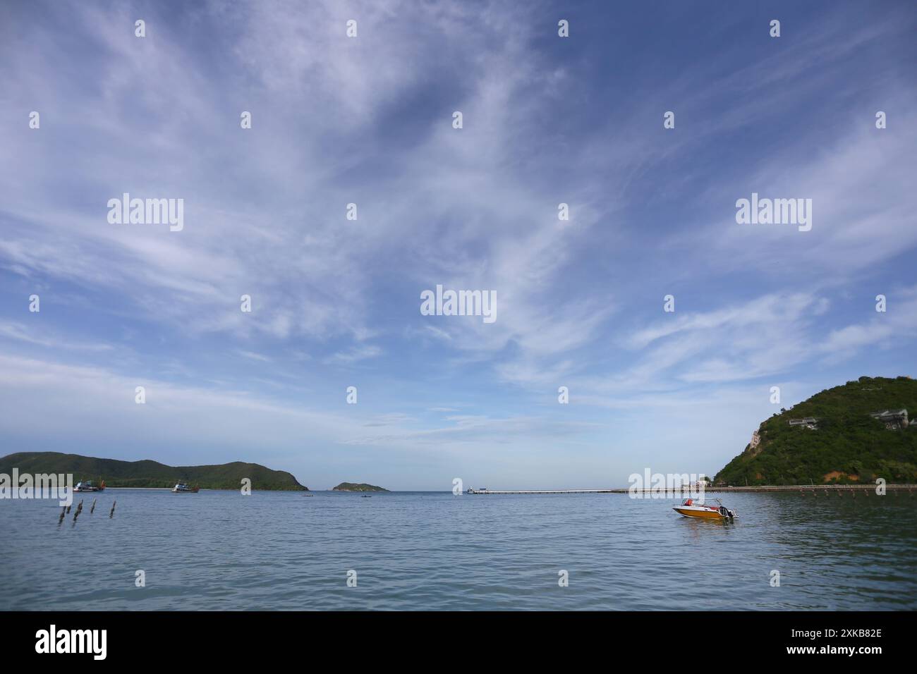 Das Meer hat schwimmende Schiffe und Berge umgeben es an einem klaren Tag mit weißen Wolken. Stockfoto