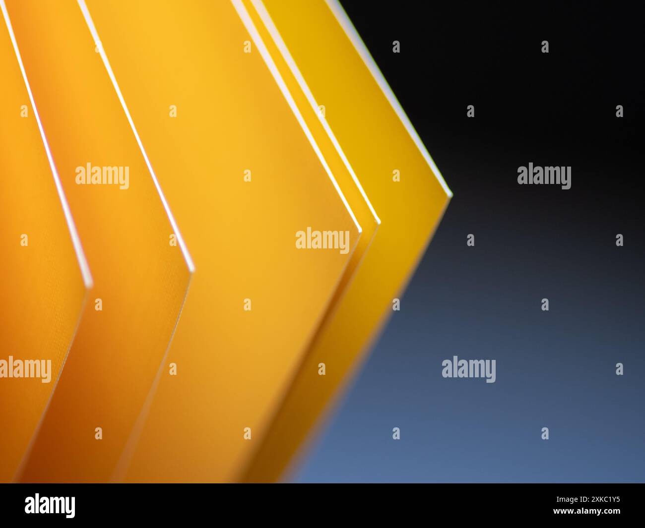 Geometrische Winkel aus leuchtendem gelbem Cardstock vor blauem und schwarzem Hintergrund Stockfoto