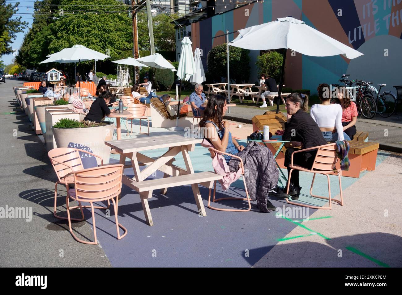 Die Leute entspannen sich im Freien in einer Straße, die nicht weit vom Verkehr entfernt ist, im Viertel South Granville, Vancouver, BC, Kanada Stockfoto