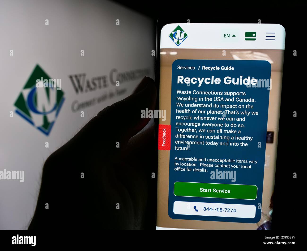 Person, die ein Mobiltelefon hält, mit der Webseite des US-Recyclingunternehmens Waste Connections Inc. Vor dem Firmenlogo. Konzentrieren Sie sich auf die Mitte des Telefondisplays. Stockfoto