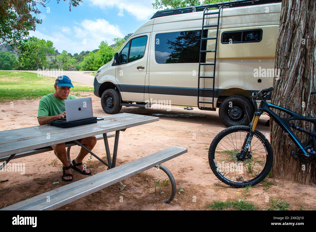 Ein Mann, der am Mac-Computer arbeitet, an einem Picknicktisch im Palo Duro Canyon State Park, Texas Stockfoto