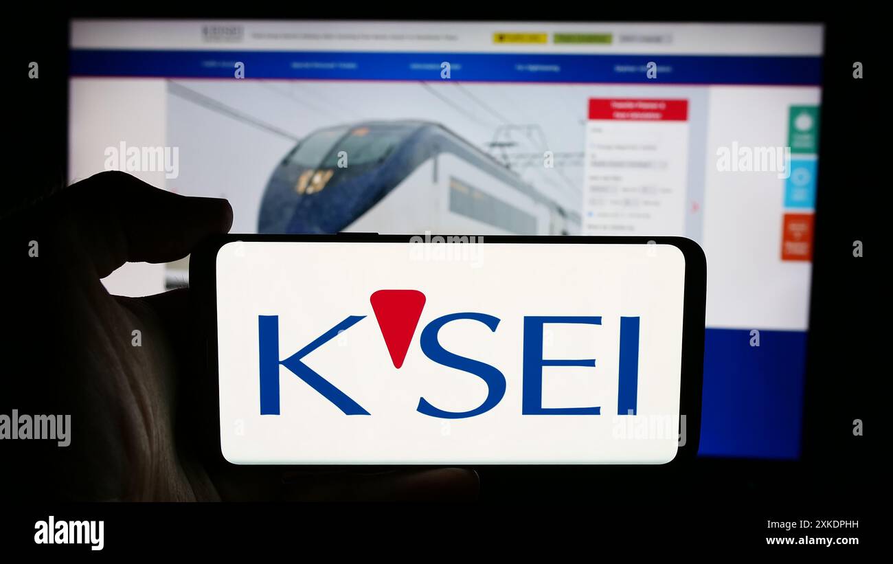 Person mit Handy mit Logo der japanischen Eisenbahngesellschaft Keisei Electric Railway Co. Ltd. Vor der Webseite. Schwerpunkt auf dem Display des Telefons. Stockfoto