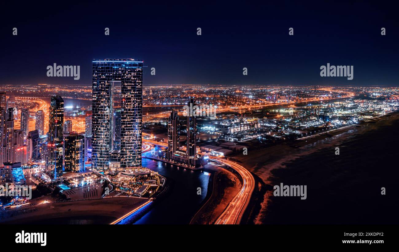 Ein Blick aus der Vogelperspektive auf Dubais Skyline bei Nacht mit beleuchteten Wolkenkratzern und einer Autobahn, die sich in die Ferne erstreckt. Stockfoto