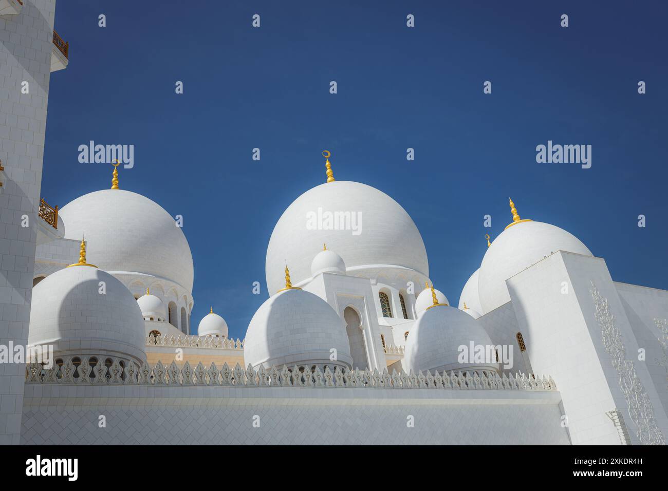 Die große Scheich-Zayed-Moschee in Abu Dhabi, VAE, mit ihren weißen Kuppeln und komplizierten Details unter einem klaren blauen Himmel. Stockfoto