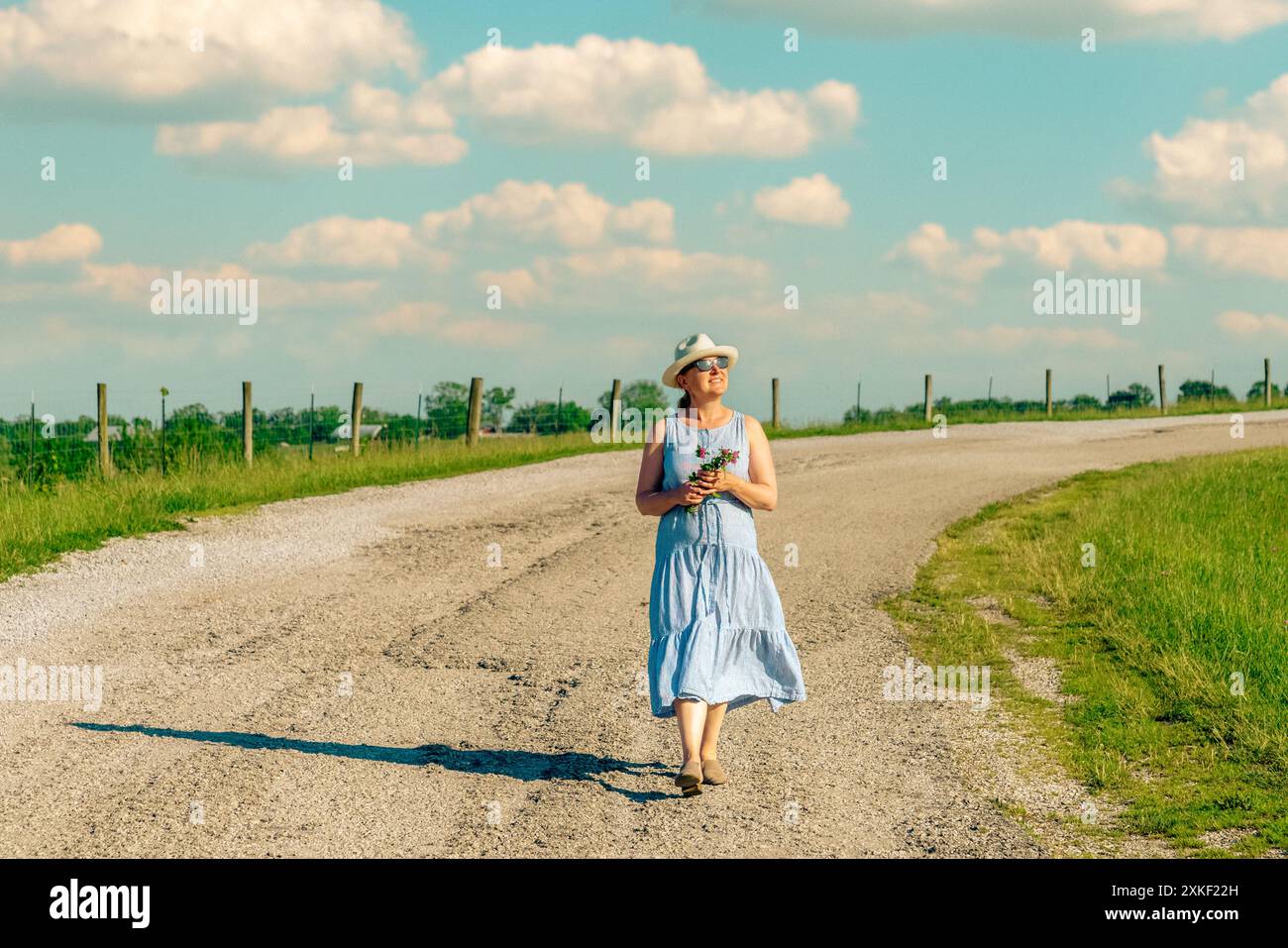 Glückliche reife Frau läuft an einem hellen Sommertag auf einer Landstraße. Stockfoto