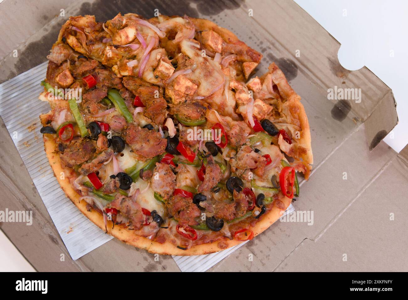 Köstliche, unordentliche Pizza, halb verschlungen und immer noch verführerisch in der Pappschachtel. Reste? Nie! Stockfoto