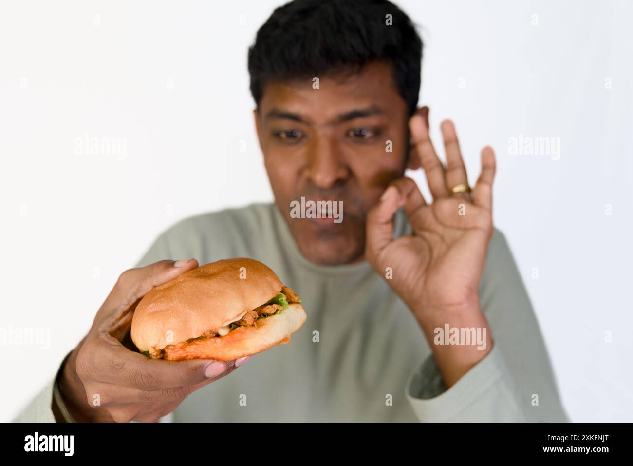 Der Mann ist aufgeregt für Ruhe, während er sich auf einen leckeren Burger vorbereitet. Stockfoto