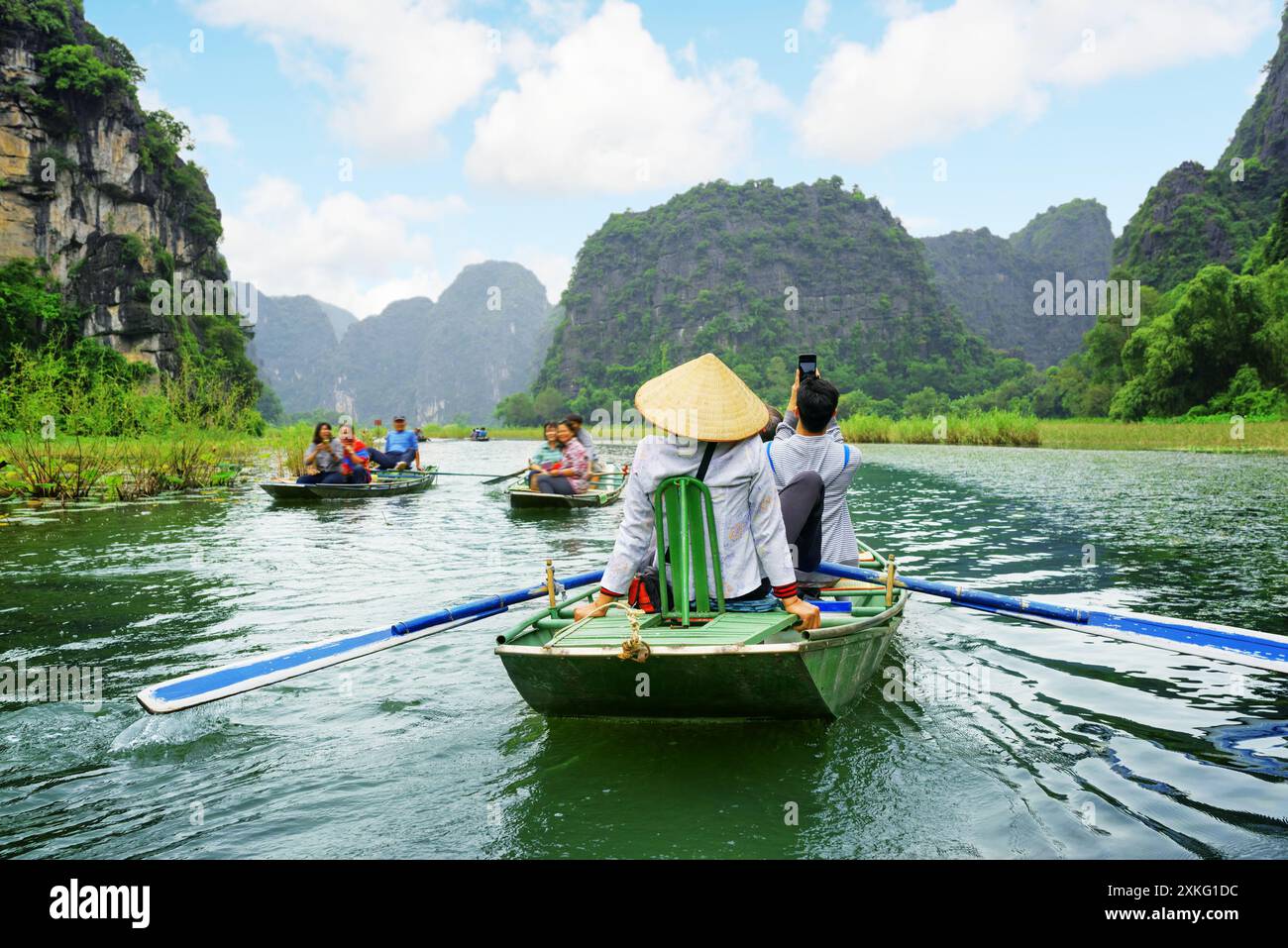 Touristen in Booten. Ruderer, die mit Füßen Ruder treiben, Vietnam Stockfoto