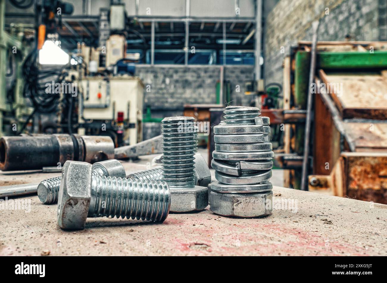 Schraubensatz auf verschwommenem Werkstatthintergrund. Entbehrliche Hardware. Sortiment Stahlschrauben Nahaufnahme Stockfoto