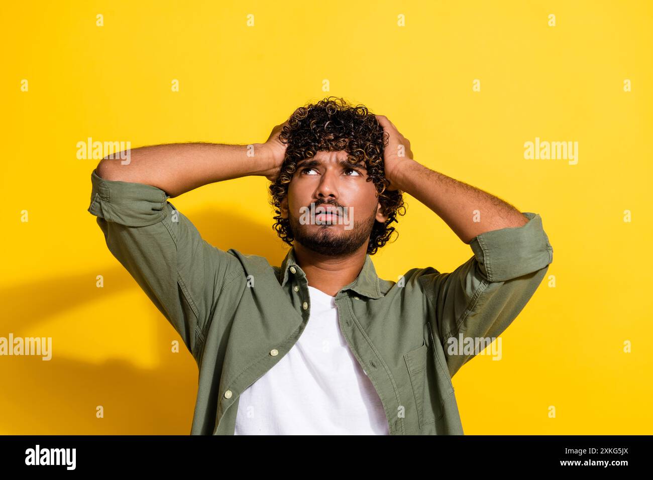 Portraitfoto des jungen latinos in khakifarbenem Hemd deprimiert betrunken berührenden Kopf leiden isoliert auf gelbem Hintergrund Stockfoto