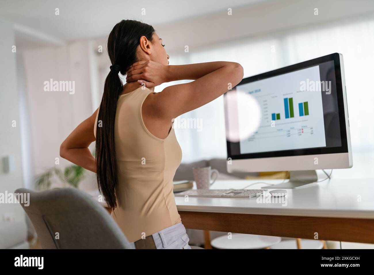 Müde Geschäftsfrau schläfrig und gelangweilt vom Sitzen am Schreibtisch für eine lange Zeit und hat ein Bürosyndrom Stockfoto