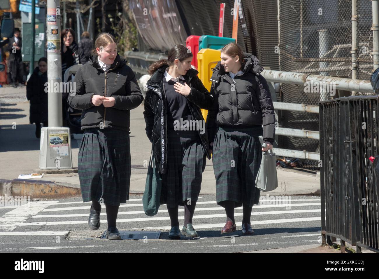 Klassenkameraden einer Pfarrschule für religiöse jüdische Mädchen gehen nach Hause, während sie ein animiertes Gespräch führen. An der Bedford Avenue in Williamsburg, NYC. Stockfoto