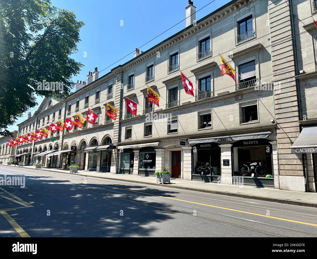 Rue de la Corraterie im Zentrum von Genf. Charakteristische Straße in der Nähe der Altstadt mit modischen Geschäften und Büros. Keine Personen. Schweizer Fahnen säumen die Stockfoto