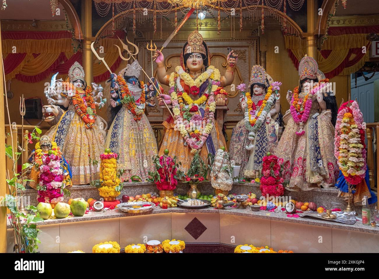 Ein Altar in einem Shakti Hindu-Tempel mit den Göttern in wunderschönen bunten Kleidern. In Queens, NYC. Die Göttin Mariamman ist die Hauptfigur. Stockfoto