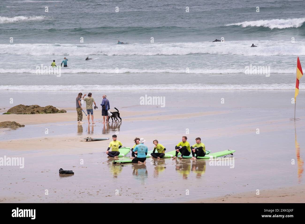 Eine Surfstunde am GT Great Western Beach. Eine Gruppe von Surfanfängern mit ihrem Surflehrer von der Escape Surf School in Newquay in Cornwall Stockfoto