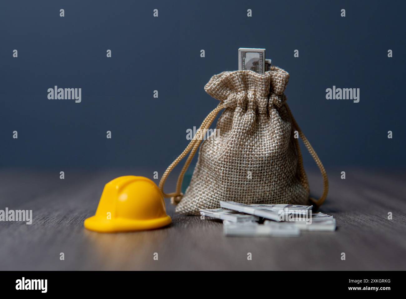 Nahaufnahme: Eine Tasche mit Geld und ein Schutzhelm auf einem Holztisch. Konzept der Mitarbeitervergütung. Stockfoto