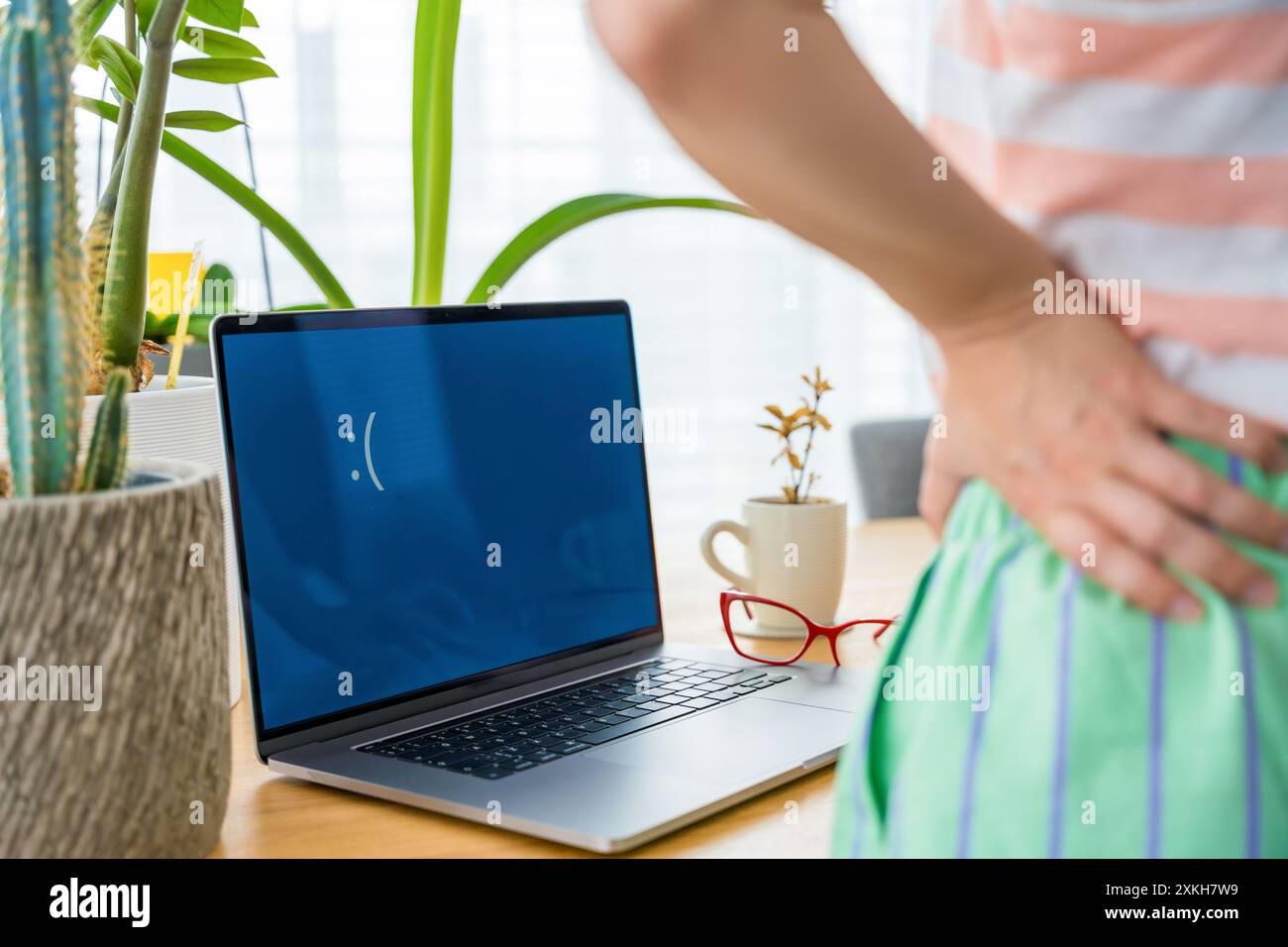 Verärgerte junge Frau, die auf traurigen Laptop-Monitor mit blauem Bildschirm auf dem Schreibtisch im Heimbüro schaut Stockfoto