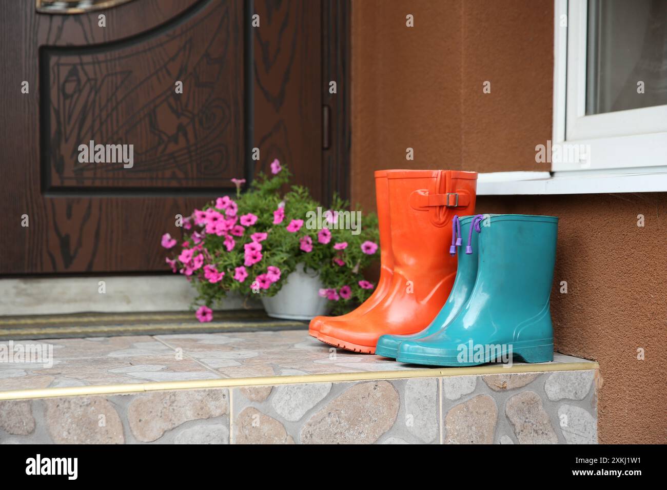 Zwei Paar Gummistiefel vor der Tür in der Nähe des Eingangs im Freien Stockfoto