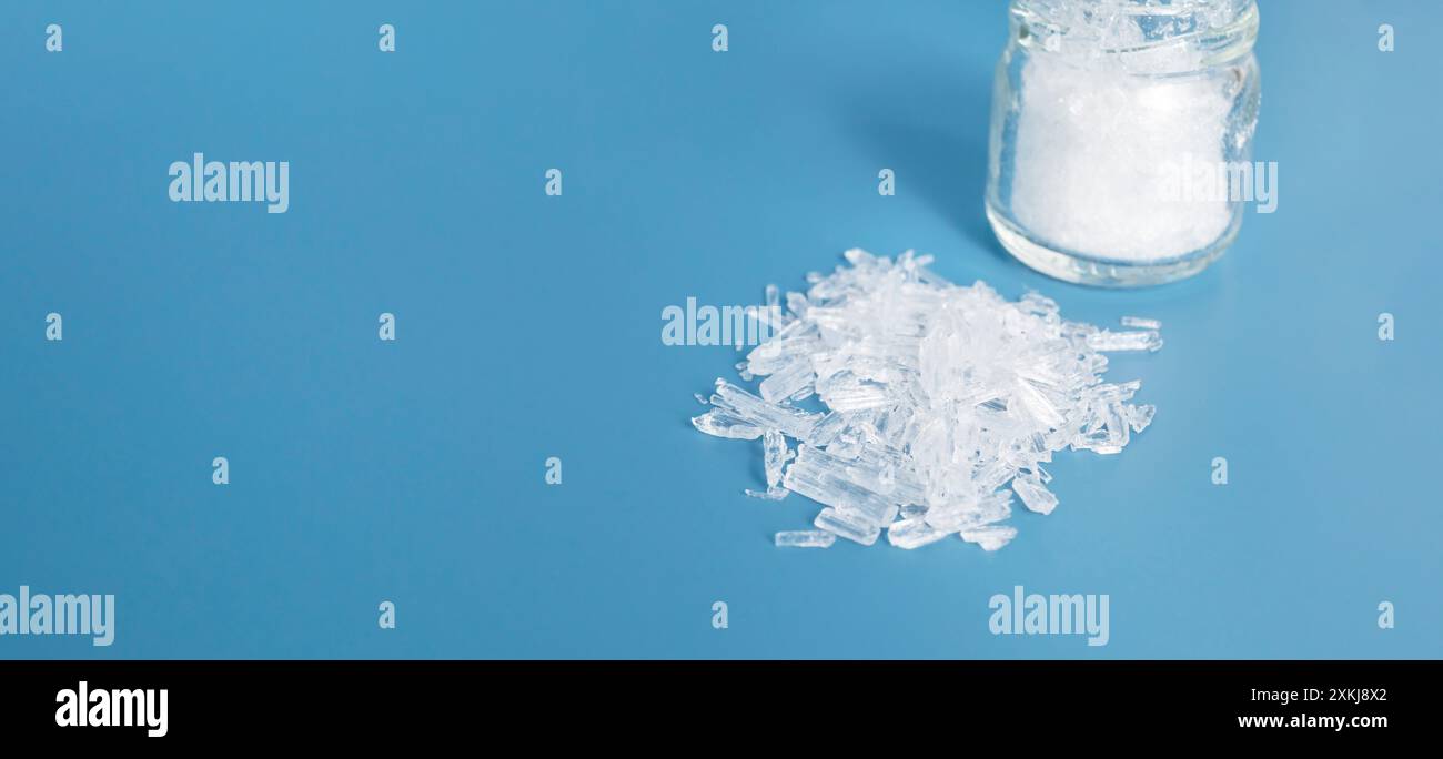 Banner Top View organischer Haufen von durchscheinenden Menthol-Kristallen auf blauem Hintergrund, Glasglas. Natürlicher Inhaltsstoff zur Herstellung von Kosmetika. Horizontal Stockfoto