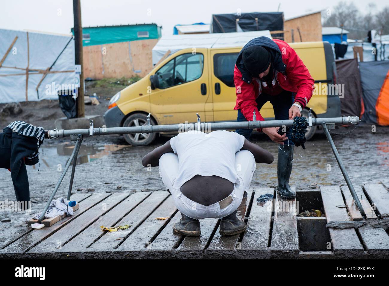 Eritreischer illegaler Migrant im Dschungel von Calais duschen und sein Gehör an einem provisorischen Wasserpunkt waschen. Calais, Frankreich. Calais der Dschungel Nord pas de Calais Frankreich Copyright: XGuidoxKoppesxPhotox Stockfoto