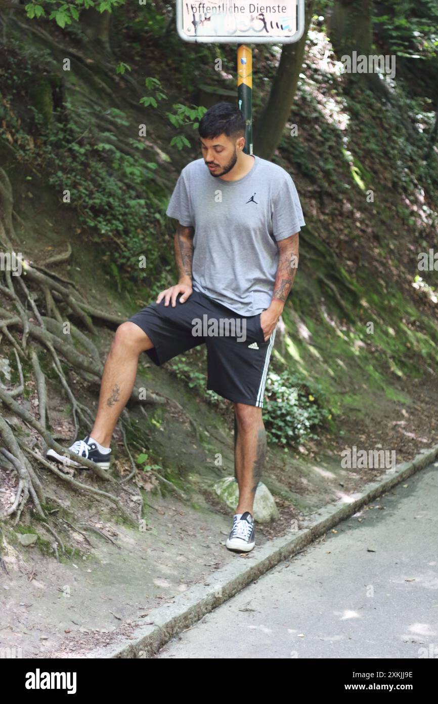 Ein lebendiges Bild mit einem jungen tätowierten Mann in Sportkleidung, der einen sonnigen Tag in der Stadt Zürich genießt. Perfekt für Themen im Zusammenhang mit urbanem li Stockfoto