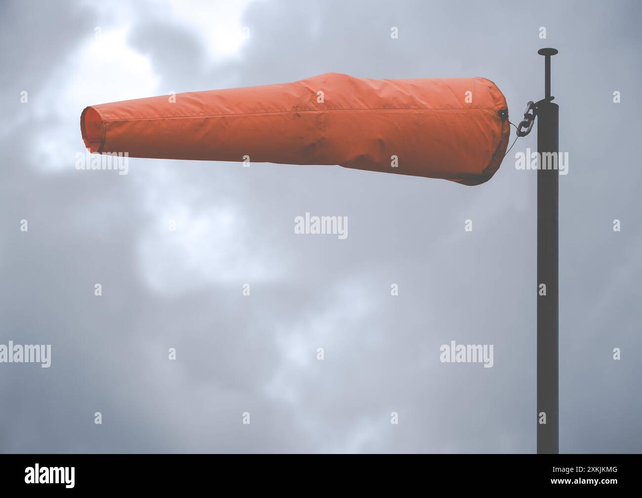 Eine leuchtend orange Windsocke an einem Flughafen an einem Sturmtag, mit Kopierraum Stockfoto