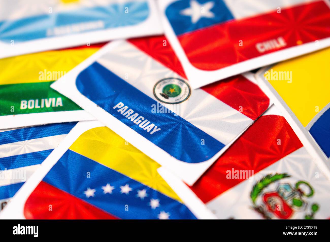 Eine Nahaufnahme verschiedener farbenfroher internationaler Flaggenaufkleber, die auf einer Oberfläche verstreut sind, mit unscharfem Hintergrund Stockfoto