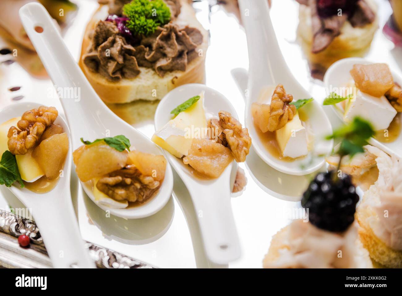 Gourmet-Vorspeisen mit Walnüssen, Käse und Obst in Keramiklöffeln auf einem Spiegeltablett. Horizontales Foto. Draufsicht. Stockfoto