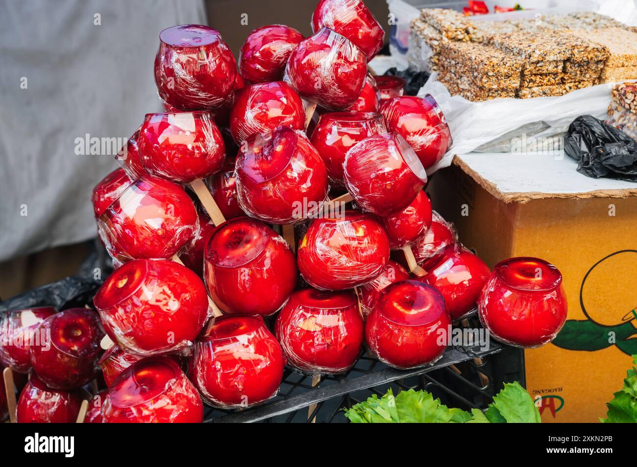 Süße Süßigkeitäpfel im Marktregal. Rote Karamelläpfel auf Stäbchen auf der Theke Stockfoto